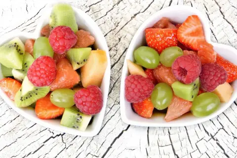Dwa sercowate talerzyki wypełnione kolorowymi owocami: truskawkami, malinami, kiwi, winogronami i grejpfrutem. Idealne przekąski 0 kcal na zdrowy deser.