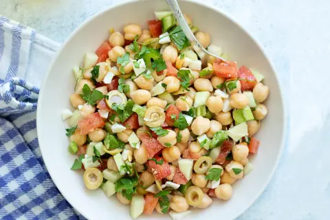 Ensalada de garbanzos fresca con tomate, pepino, aceitunas y perejil, lista para disfrutar.