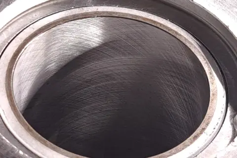 Metalowy cylinder z widocznymi śladami obróbki. Wnętrze, czyli big bore, jest ciemne i lekko błyszczące.