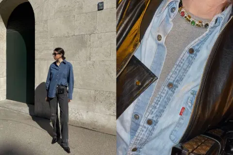 Look di tendenza: camicia jeans aperta su t-shirt grigia, jeans scuri e borsa a tracolla. Dettagli di stile con collana colorata e giacca in pelle.