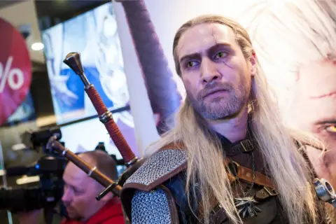 Geralt z Rivii, wiedźmin z blizną na twarzy, z dwoma mieczami za plecami.