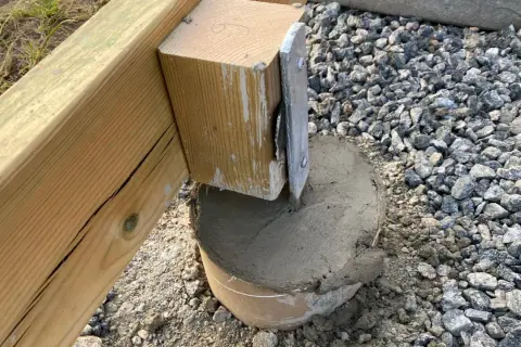 Nygjuten betong runt en stolpe som ska bära en altan. Plintavståndet är viktigt för stabiliteten.