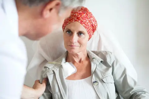 Ärztin spricht mit Patientin, die eine Kopfbedeckung trägt, während sie eine hyperthermie therapie erhält.