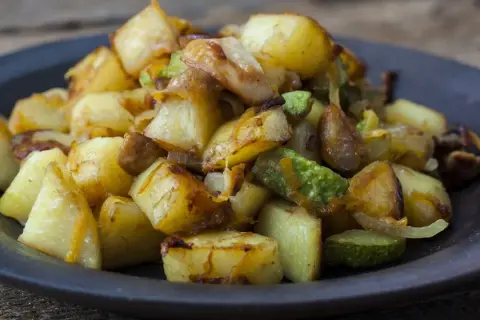 Un piatto invitante di patate e zucchine al forno, dorate e saporite, pronte per essere gustate.