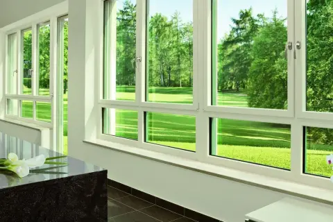 Amplias ventanas prefabricadas PVC con vistas a un exuberante jardín verde.