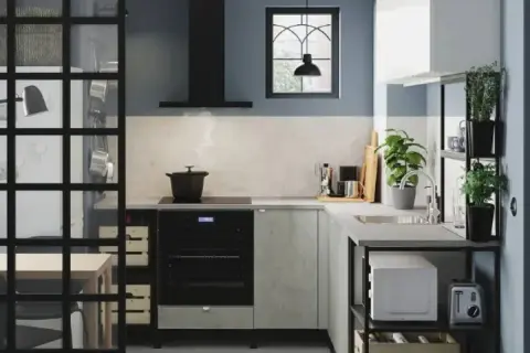 Cocina estrecha y pequeña con electrodomésticos modernos, plantas y una ventana con rejas.