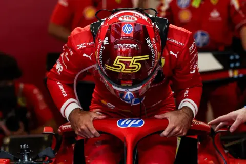 Carlos Sainz, piloto de Ferrari, se inclina sobre el volante de su monoplaza, con el casco rojo y el número 55.