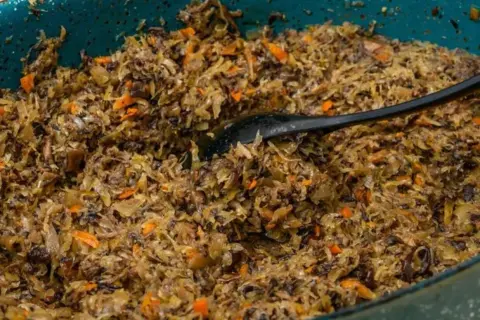 Pyszne, domowe pierogi z kapustą i grzybami, gotowe do podania. Czarna łyżka miesza aromatyczny farsz.