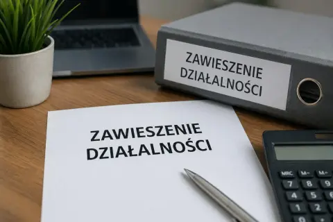 Dokumenty dotyczące zawieszenia działalności i ZUS leżą na biurku obok kalkulatora i laptopa.