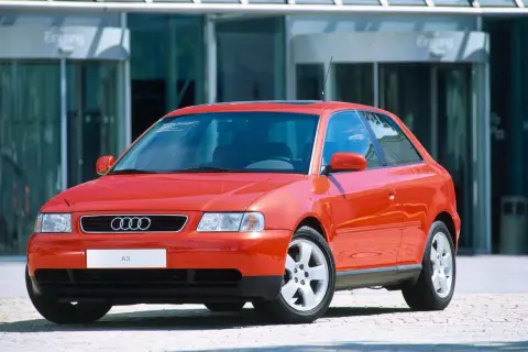 Roter Audi A3 vor einem modernen Gebäude. Ein Klassiker, der bald das Youngtimer Kennzeichen tragen darf.