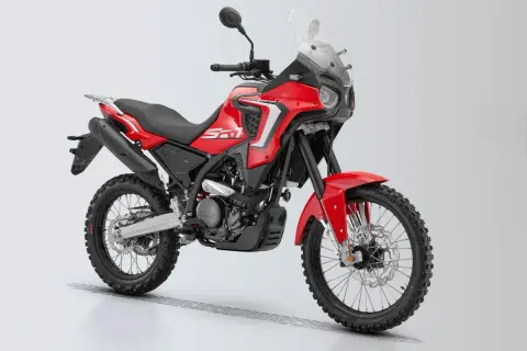 Czerwony motocykl turystyczny z czarnymi oponami terenowymi i dużą szybą.
