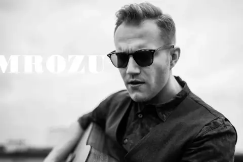 Mrozu w okularach przeciwsłonecznych gra na gitarze. Jego mrozu utwory poruszają serca słuchaczy.