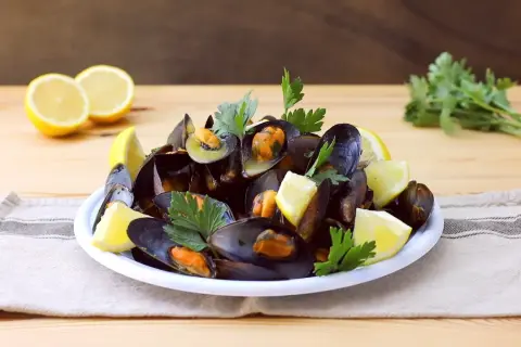 Un piatto invitante di impepata di cozze, guarnito con spicchi di limone fresco e prezzemolo, pronto per essere gustato.