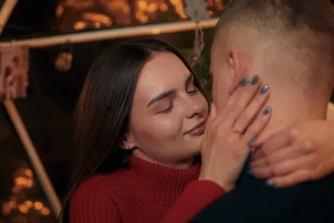 Bliska, intymna chwila pary. Ona zamyka oczy, dotykając jego policzka. Sekret jak rozkochać w sobie faceta na odległość? Bliskość, nawet w oddali.