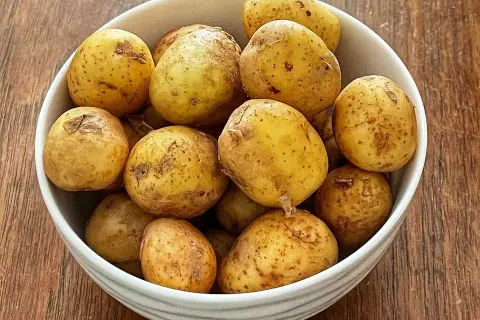 En skål med färskpotatis, redo att koka. Perfekt för en svensk sommarmåltid.