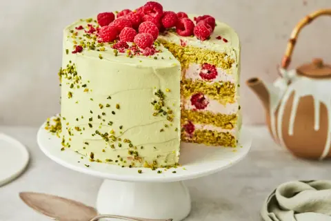 Ein köstlicher Pistazien Cheesecake mit frischen Himbeeren und gehackten Pistazien, bereit zum Servieren.