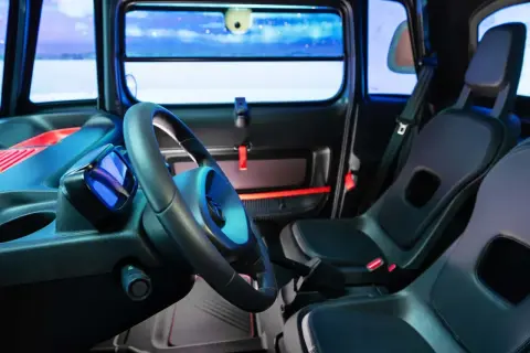 Interni Citroën Ami: volante, sedili neri e un display blu. Un'atmosfera futuristica per la mobilità urbana.
