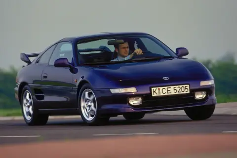 Mężczyzna prowadzi fioletowe Toyota MR2 SW20 po krętej drodze.