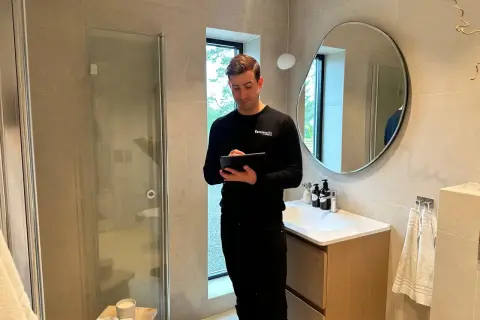 Man med surfplatta i ett modernt badrum, redo för renovering badrum.