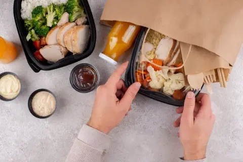 Dwa pudełka z jedzeniem na wynos: kurczak z ryżem i warzywami, sosy, sok. Idealny lunch co to?