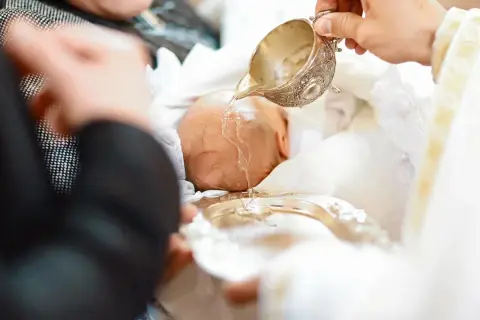 Chrzest niemowlęcia, kapłan polewa głowę wodą święconą. Wkrótce otrzyma jedno z pięknych, świętych imion męskich.