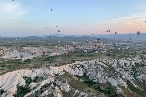Setki balonów na gorące powietrze unoszą się nad skalistym krajobrazem Kapadocji o wschodzie słońca. To marzenie o podróżowaniu, które można zrealizować, szukając sposobów, jak tanio podróżować.