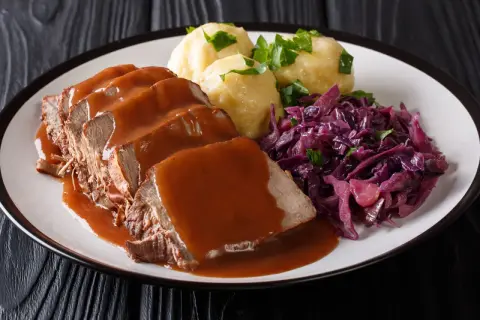 Ein Teller mit saftigem Sauerbraten, Klößen und Rotkohl. Perfekt für die Schwangerschaft, wenn man Lust auf Hausmannskost hat.