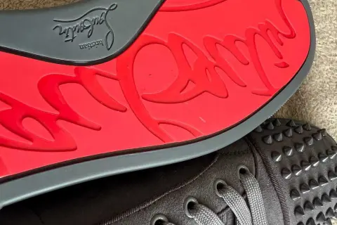 Czerwona podeszwa z logo Christian Louboutin i ćwieki na butach. Zastanawiasz się, ile kosztują buty Christiana Louboutina?