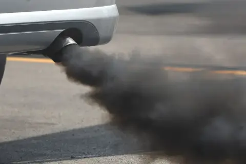 El tubo de escape de un coche emite una densa nube de humo negro, contaminando el aire.
