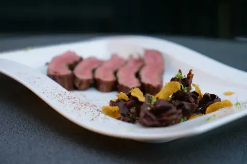 Saftiges Flank Steak, in Scheiben geschnitten, serviert mit dunkler Schokolade und knusprigen Chips.