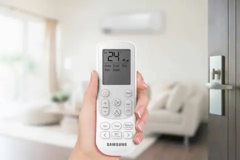 Mano che tiene il telecomando di un condizionatore Samsung. Il display mostra 24°C, Auto, Cool, Dry, Fan, Heat. Il significato di un condizionatore potente è il comfort.