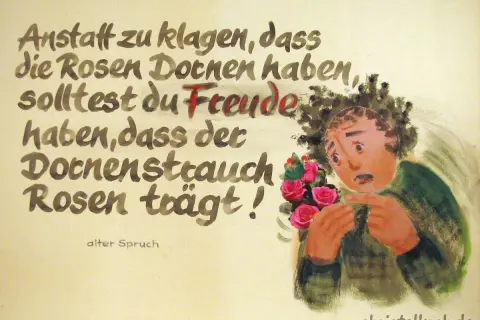 Lebensweisheiten alter Spruch: Statt über Dornen zu klagen, freue dich, dass Rosen wachsen. Ein Mann mit Rosenstrauß sticht sich in den Finger.