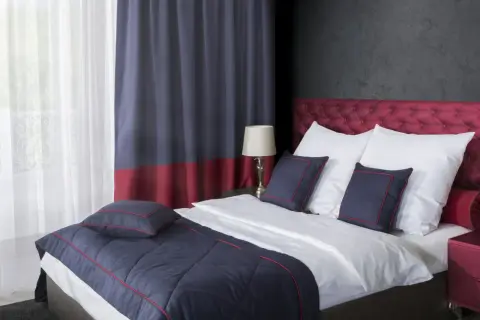Eleganckie łóżko z pikowanym zagłówkiem, białą pościelą i granatowymi poduszkami. Pokazuje, jak pościelić łóżko w stylu hotelowym.