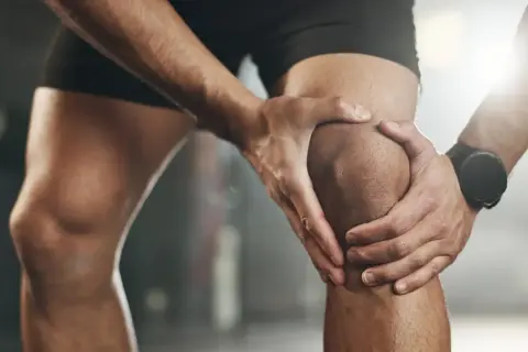Sportler hält schmerzendes Knie, deutet auf eine mögliche Kreuzbandriss Schwellung hin.