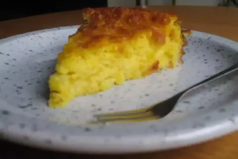 Una rebanada de torta de maiz dorada y esponjosa en un plato, lista para ser disfrutada con un tenedor.
