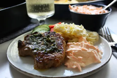 En saftig kotlett i ugn med örter, serverad med potatisgratäng och en krämig morotsallad. En perfekt middag!