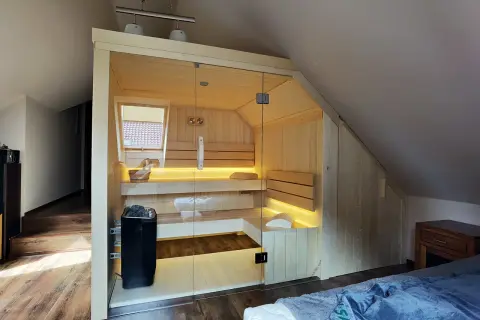 Nowoczesna sauna w domu, z przeszklonymi drzwiami i nastrojowym oświetleniem, idealna do relaksu.