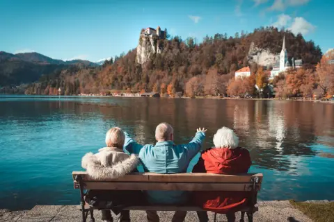 Trzech seniorów cieszy się widokiem zamku na skale i jeziora. Idealne wczasy pod gruszą dla emeryta.