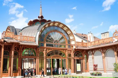 L'architecture Art Nouveau du Palais Lumière à Évian-les-Bains, avec ses vitraux colorés et sa structure en bois, sous un ciel bleu.