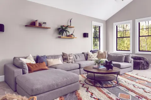Gemütliches Wohnzimmer mit großem Ecksofa, Kaffeetisch und einem auffälligen Teppich im Boho-Stil, der den aktuellen Teppich Trend widerspiegelt.