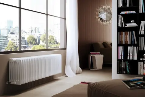Un elegante termosifone bianco sotto una grande finestra con vista sulla città.