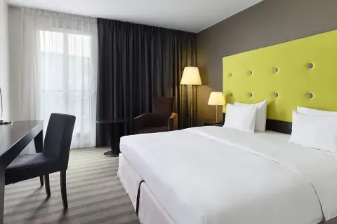 Pokój hotelowy z łóżkiem, biurkiem i fotelem.