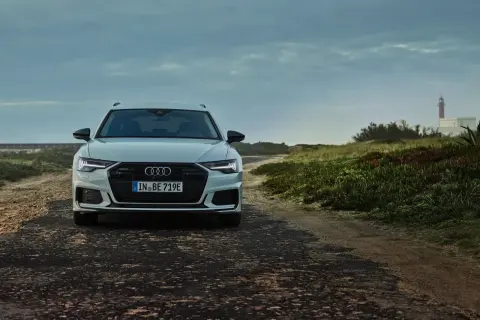 Audi A6 Avant blanche sur une route côtière. La plaque d'immatriculation "IN BE 719E" permet de connaître le modèle de voiture.