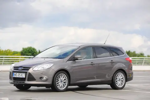 Szary Ford Focus MK3 kombi, z widocznymi reflektorami i felgami. Idealny do miasta i na wakacje, z pewnością z dobrymi żarówkami.