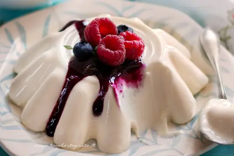 Deliziosa panna cotta con frutti di bosco e salsa ai mirtilli, servita su un piatto decorato.