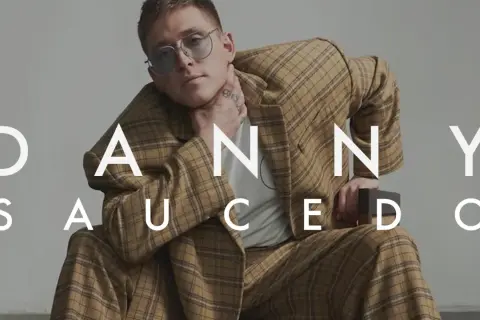Danny Saucedo i hans ursprung, klädd i en rutig kostym och med glasögon.