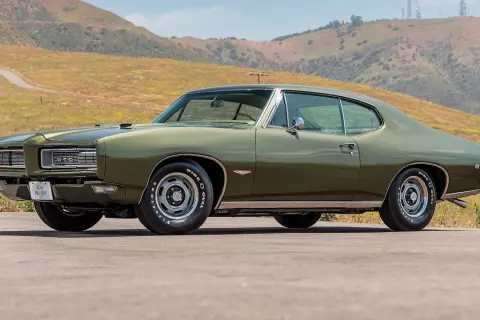 Zielony Pontiac GTO z 1969 roku na tle wzgórz. Klasyk amerykańskiej motoryzacji.