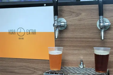 Dwa piwa w plastikowych kubkach pod kranikami. Jedno jasne, drugie ciemne. Logo "Hora Extra Beer Bike" z boku. Idealne na piwo bez chmielu.
