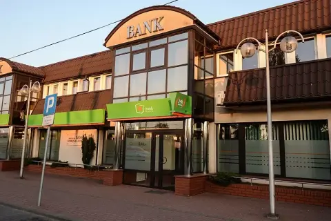 Budynek banku z zielonym neonem i napisem "BANK". W tle widać parking, co może sugerować upadłe banki w Polsce.