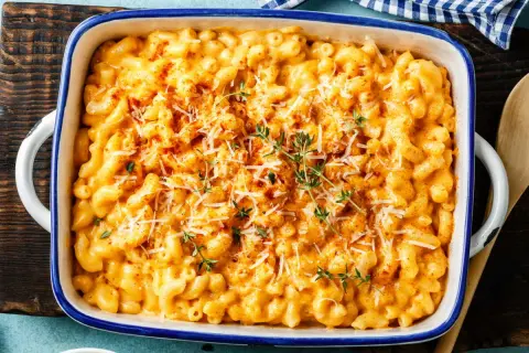 Gratin de pâtes crémeux et doré, garni de fromage râpé et de thym frais.